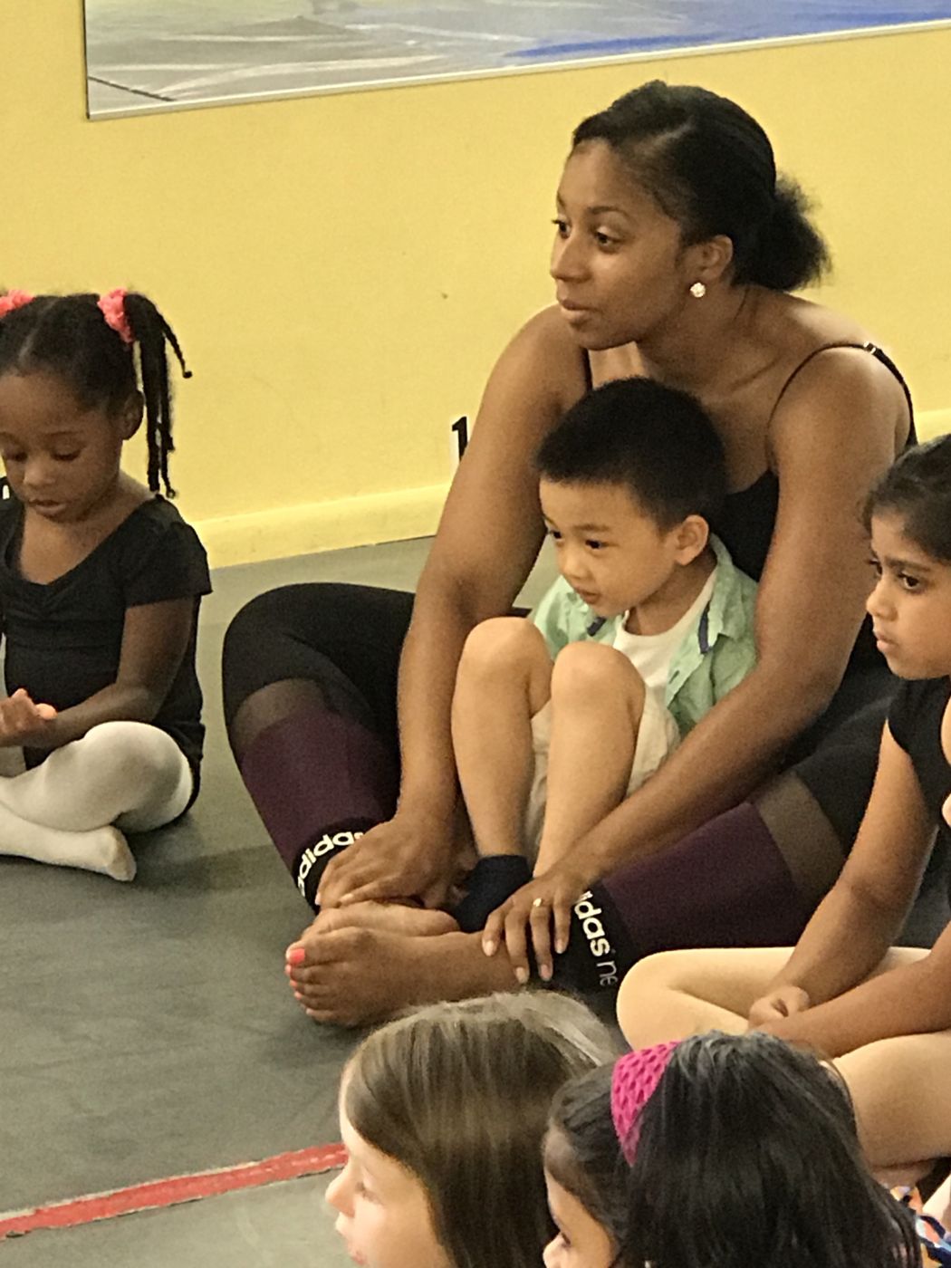 A teacher sitting with a young boy in her lap during circle time with the class