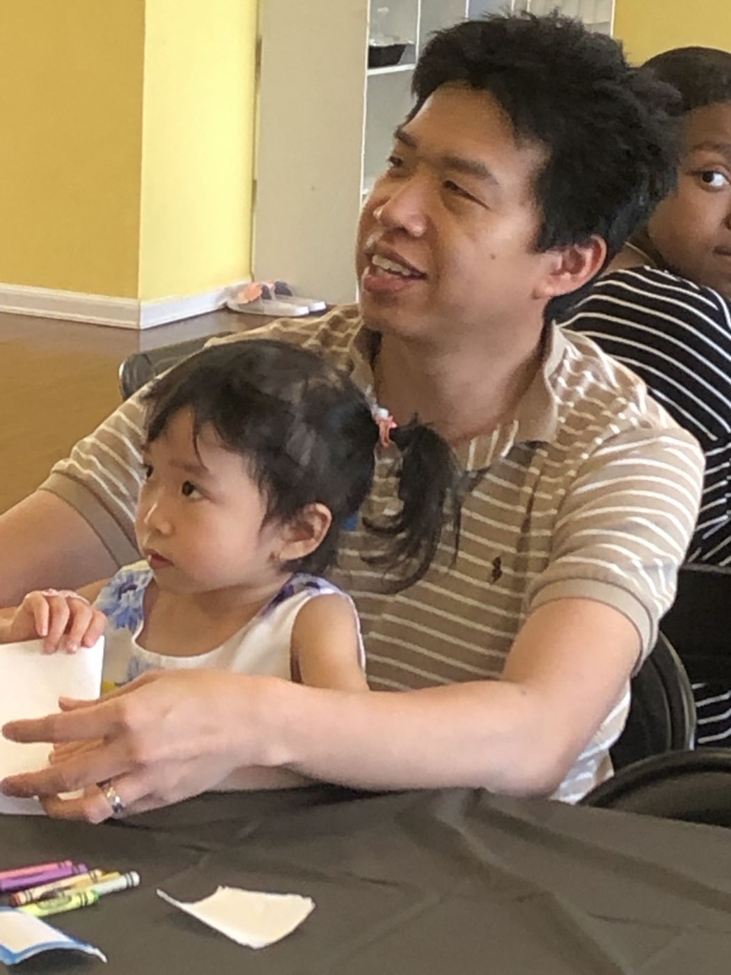 A dad and his toddler working on a coloring page together at the studio