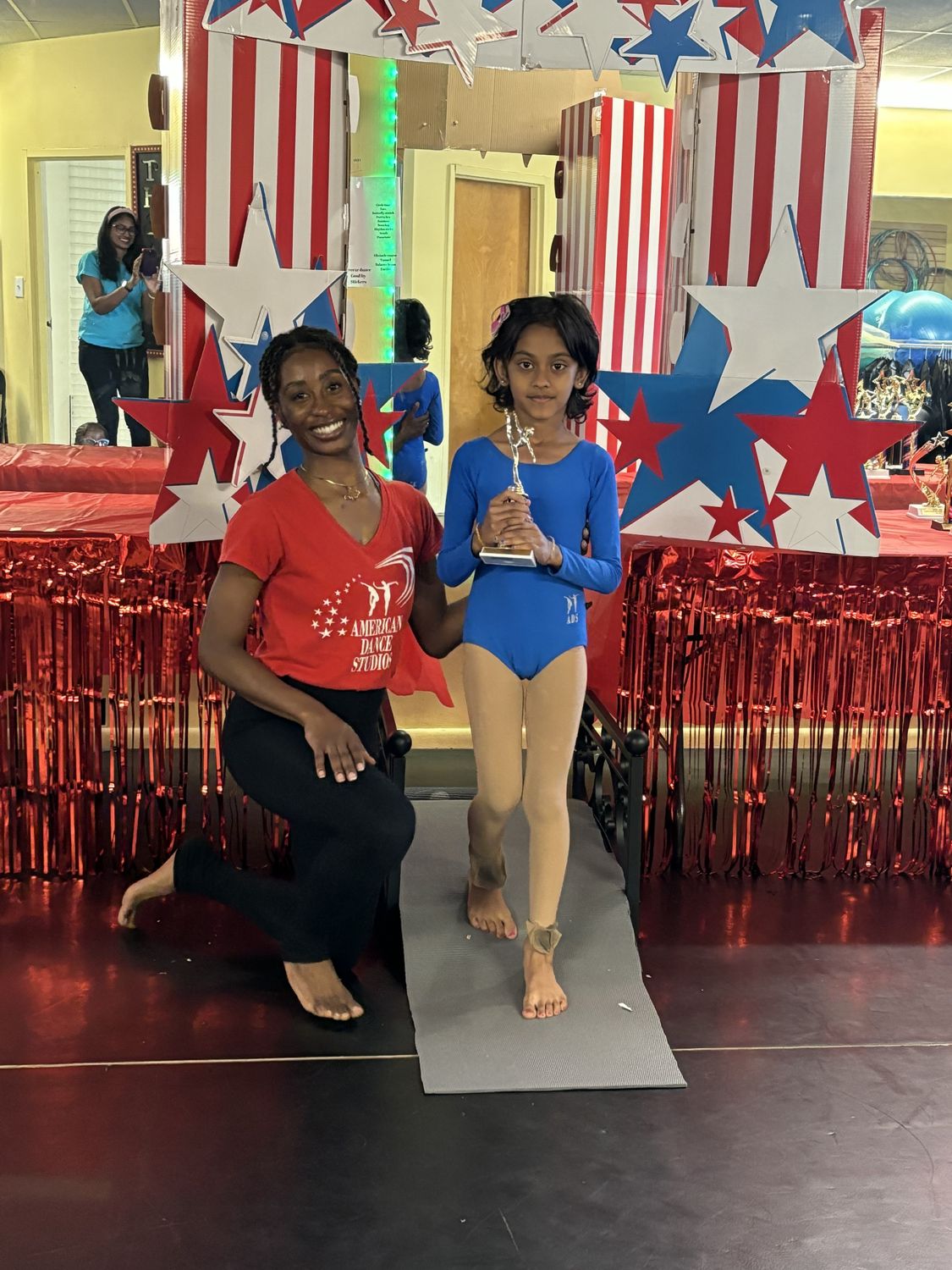 A dancer crossing the graduation bridge with her trophy beside her teacher