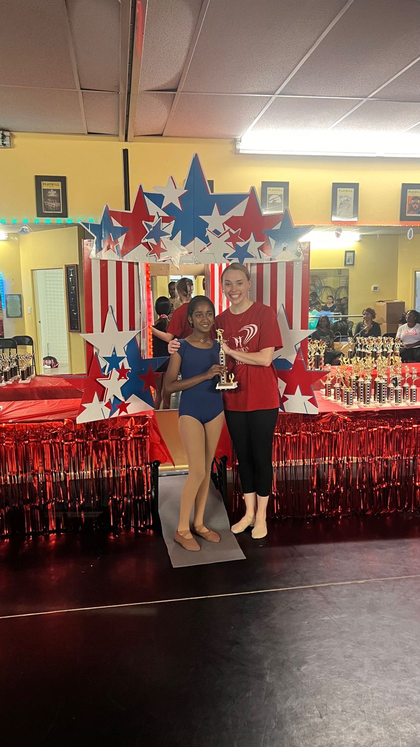 A teen ballet student and her teacher with her graduation trophy