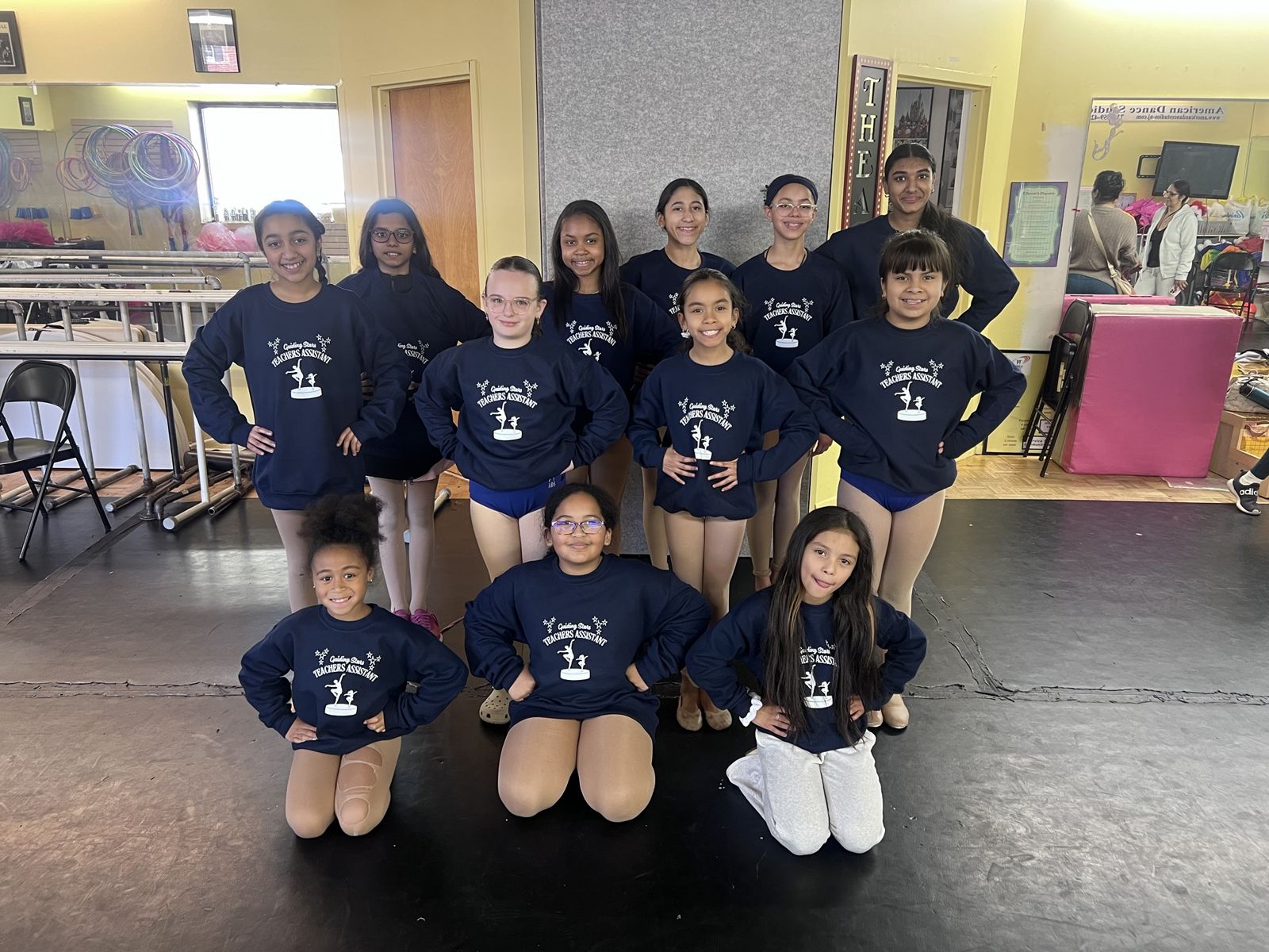 Guiding Stars teacher assistants in navy sweatshirts posing together in the studio
