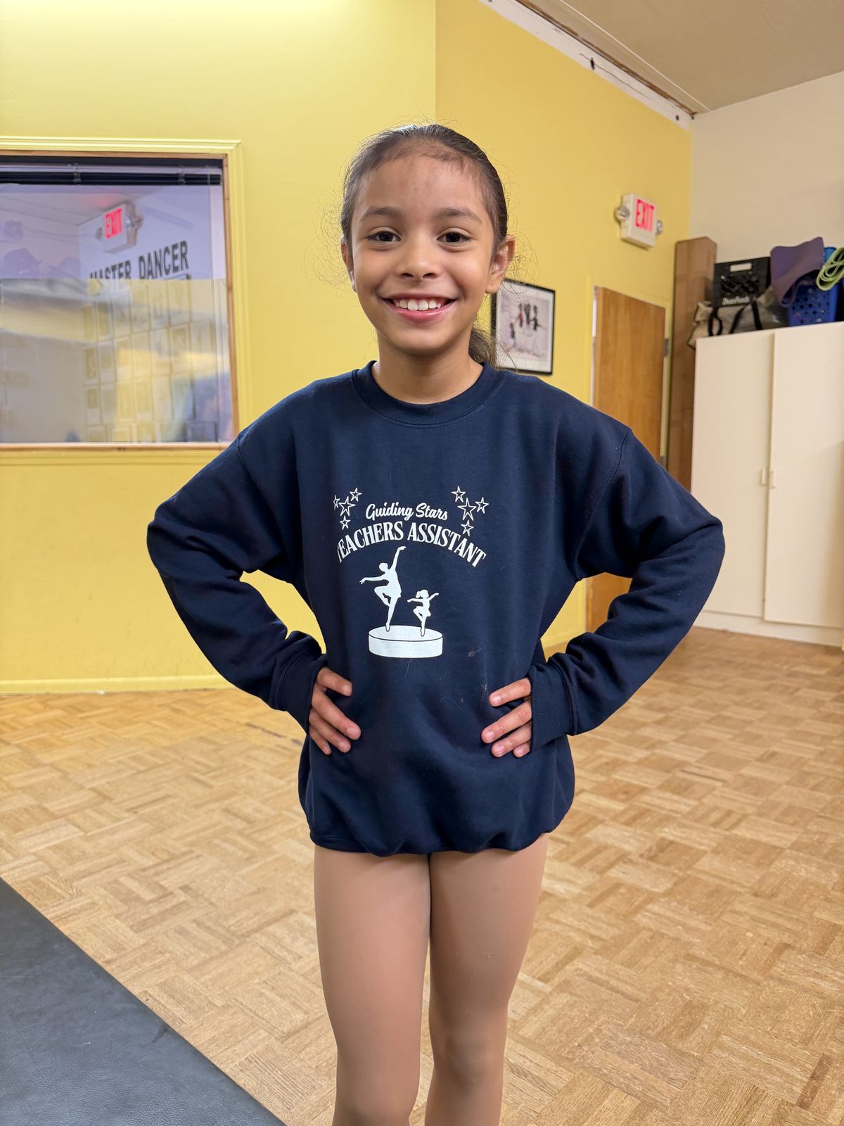 A smiling junior teacher assistant in her Guiding Stars sweatshirt