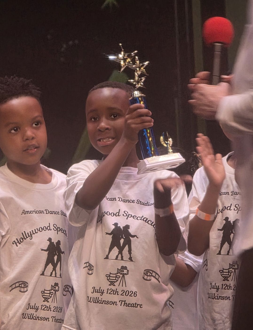 A Rhythm Crew dancer lifting his trophy on stage