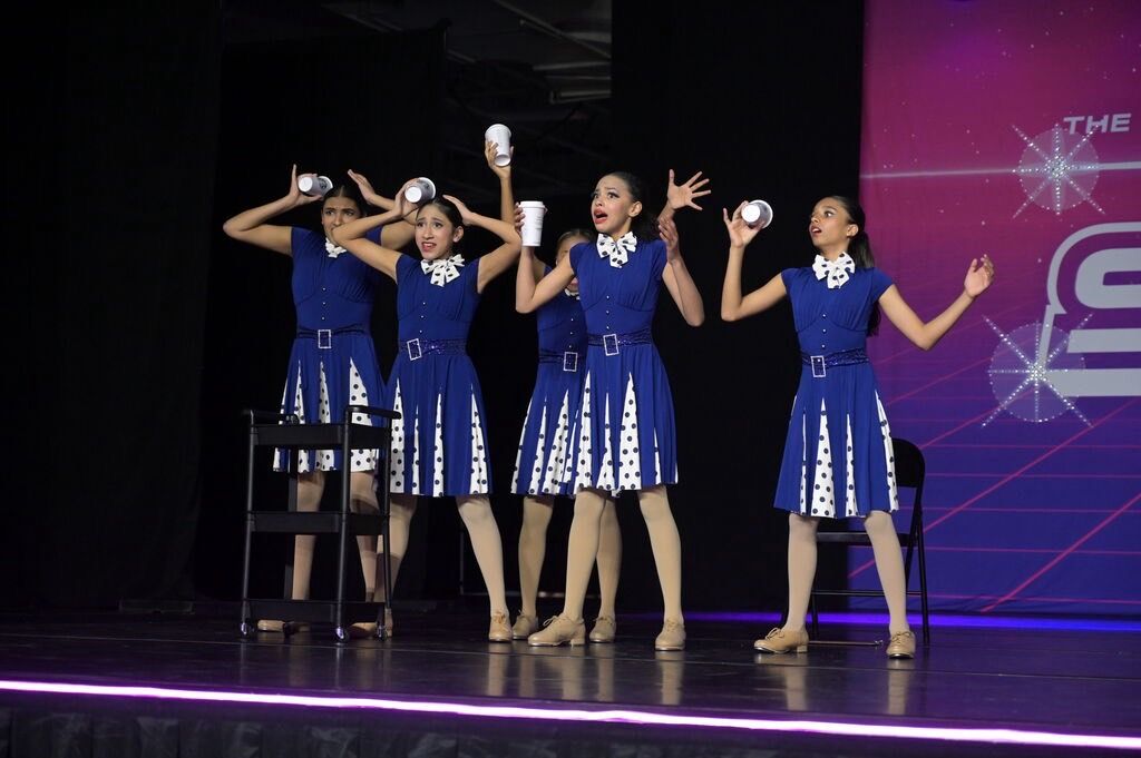 Tap dancers in blue polka-dot dresses performing at a competition