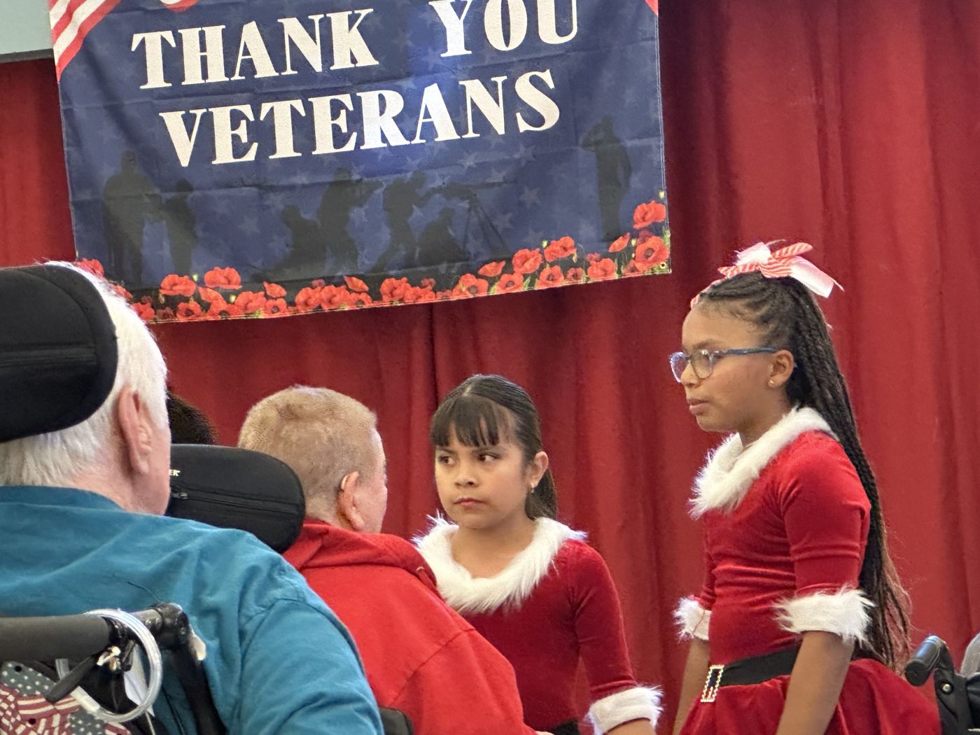 ADS dancers in red and white holiday costumes greeting veterans at the veterans hospital